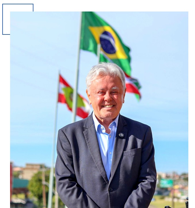 Paulo Alceu com as bandeiras do Brasil e Santa Catarina ao fundo
